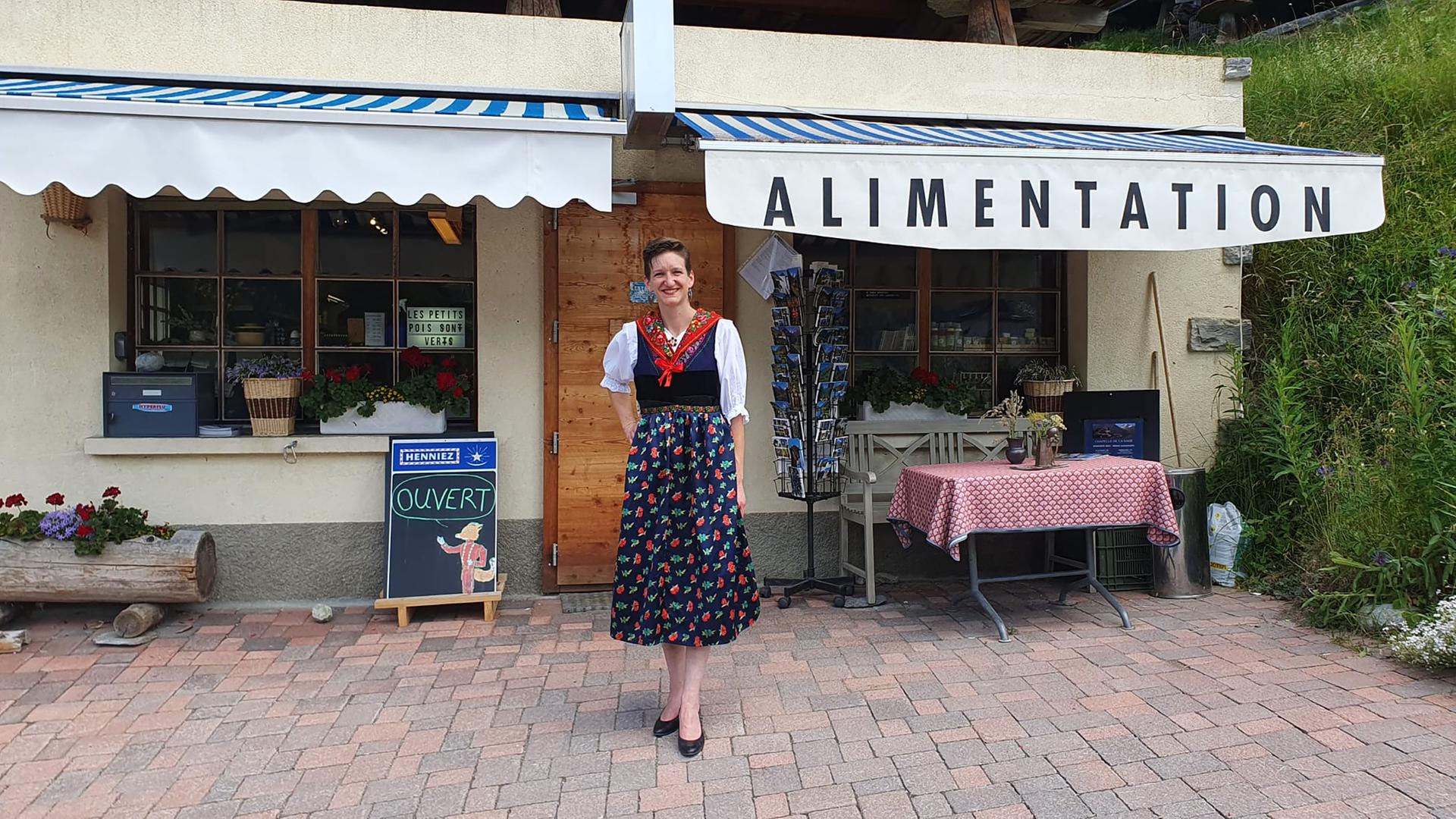 Eine Frau in einem Dirndl steht vor einem Laden