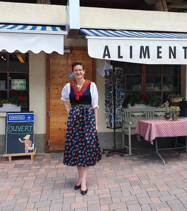 Eine Frau in einem Dirndl steht vor einem Laden