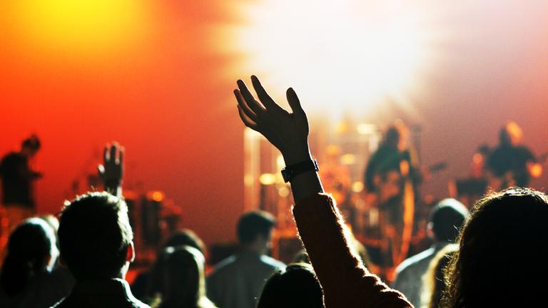 Unscharfe Menschenmenge tanz vor Bühne mit Band in grellem Licht