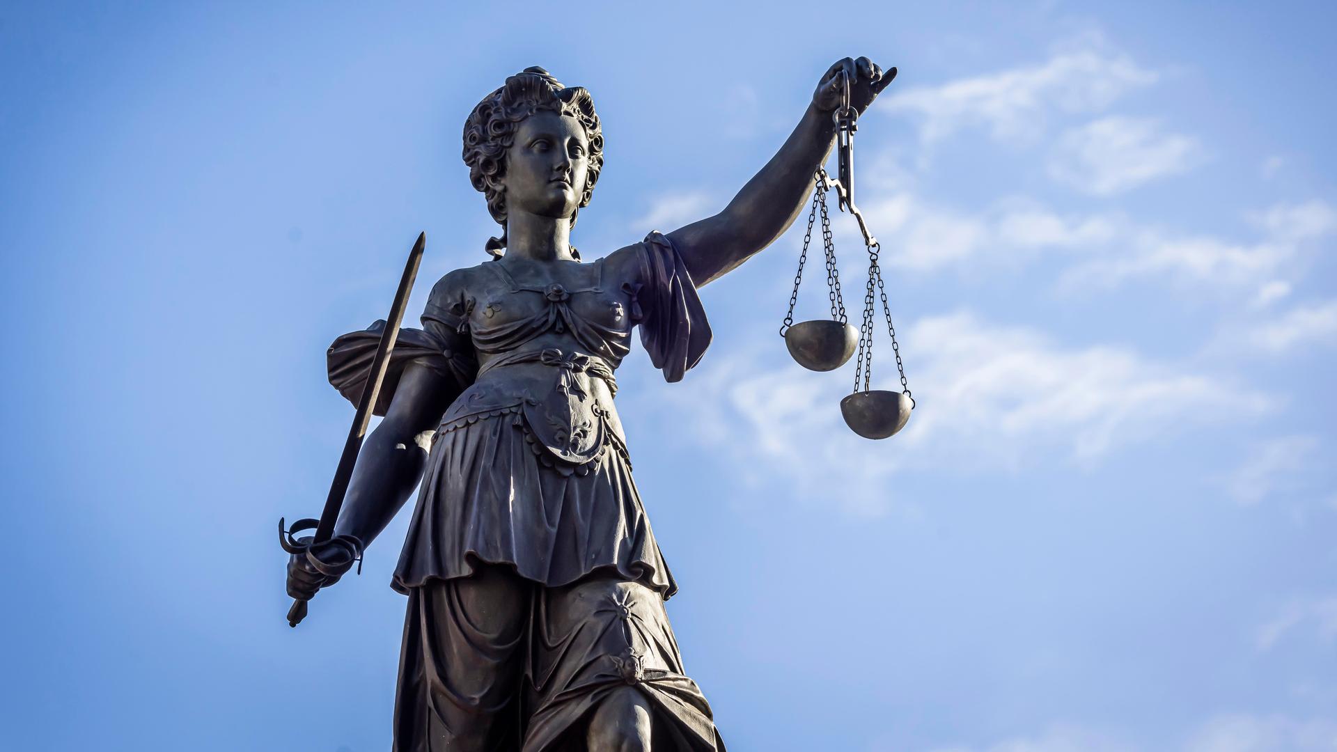 Staute der Justitia aus der Froschperspektive vor blauem Himmel