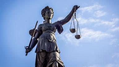 Staute der Justitia aus der Froschperspektive vor blauem Himmel