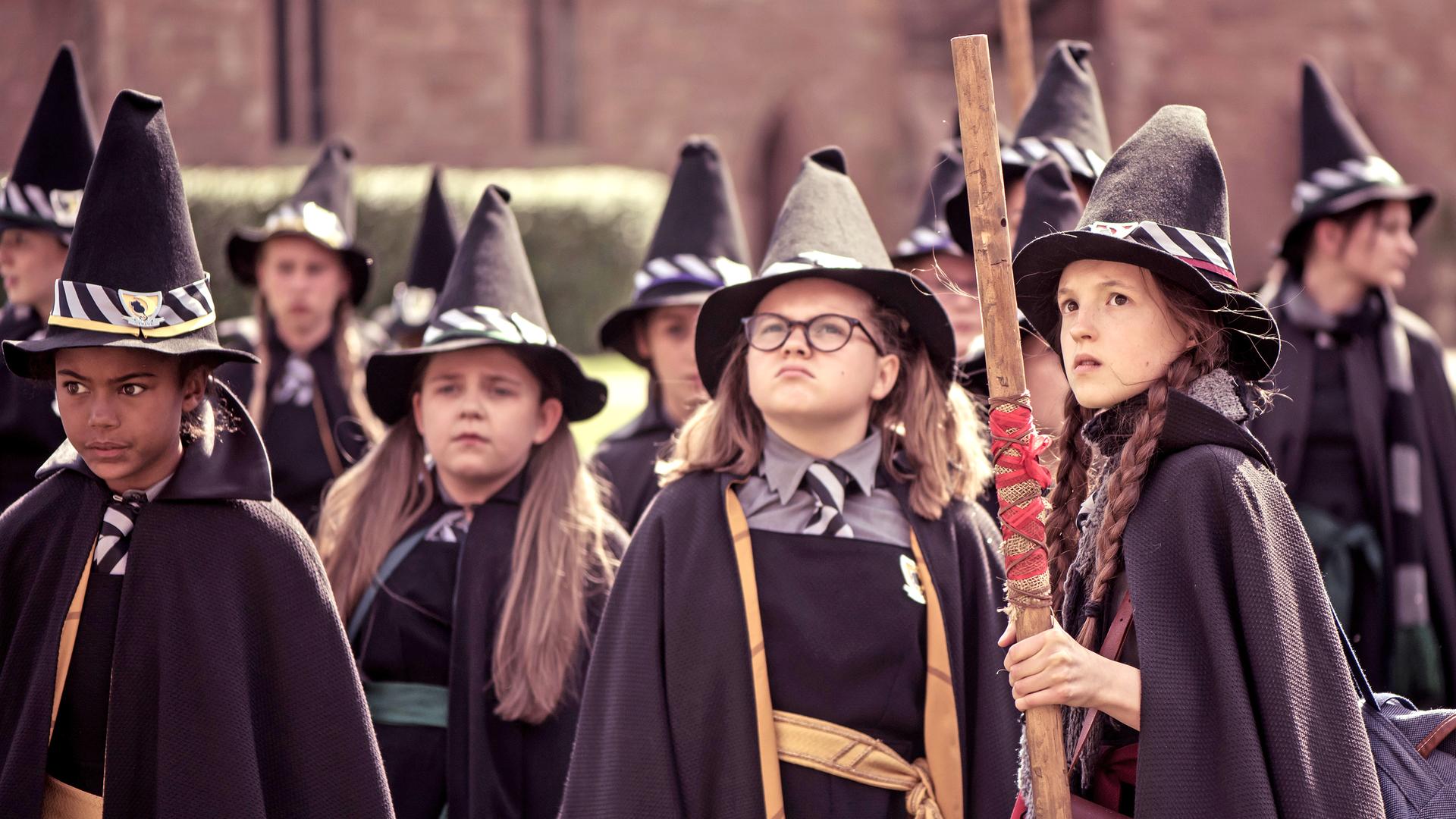 Mildred und Maude blicken erstaunt nach oben. Dabei halten sie ihre Besen in den Händen.