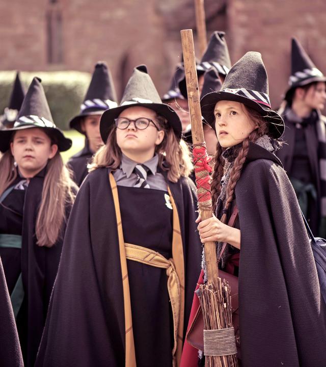 Mildred und Maude blicken erstaunt nach oben. Dabei halten sie ihre Besen in den Händen.