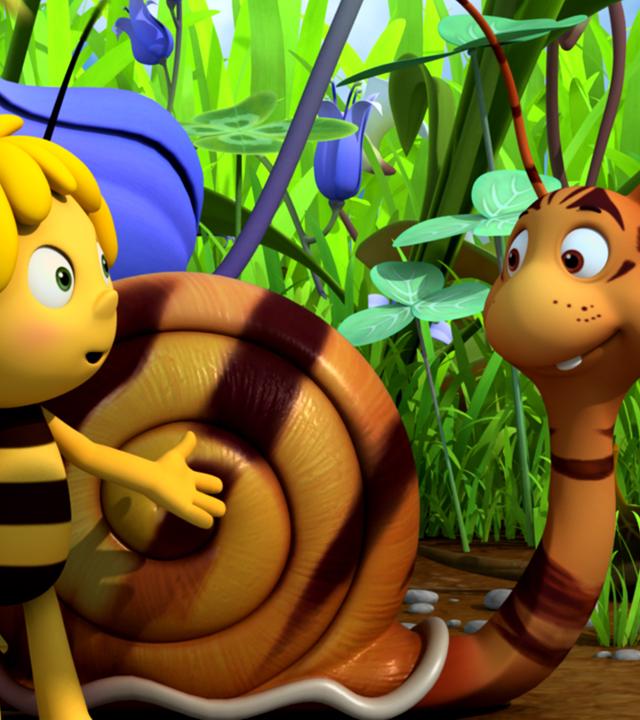 Rufus hat dank Maja eine ordentliche Tarnung. Sein Gesicht und Schneckenhaus sind mit braunen Streifen übersäht. Maja steht zuversichtlich daneben.