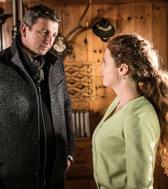 "Der Bergdoktor: Getrennte Wege (1)": Dr. Gruber (Hans Sigl) und Physiotherapeutin Erianna Kolas (Anja Antonowicz) stehen sich in einem Zimmer gegenüber und unterhalten sich.