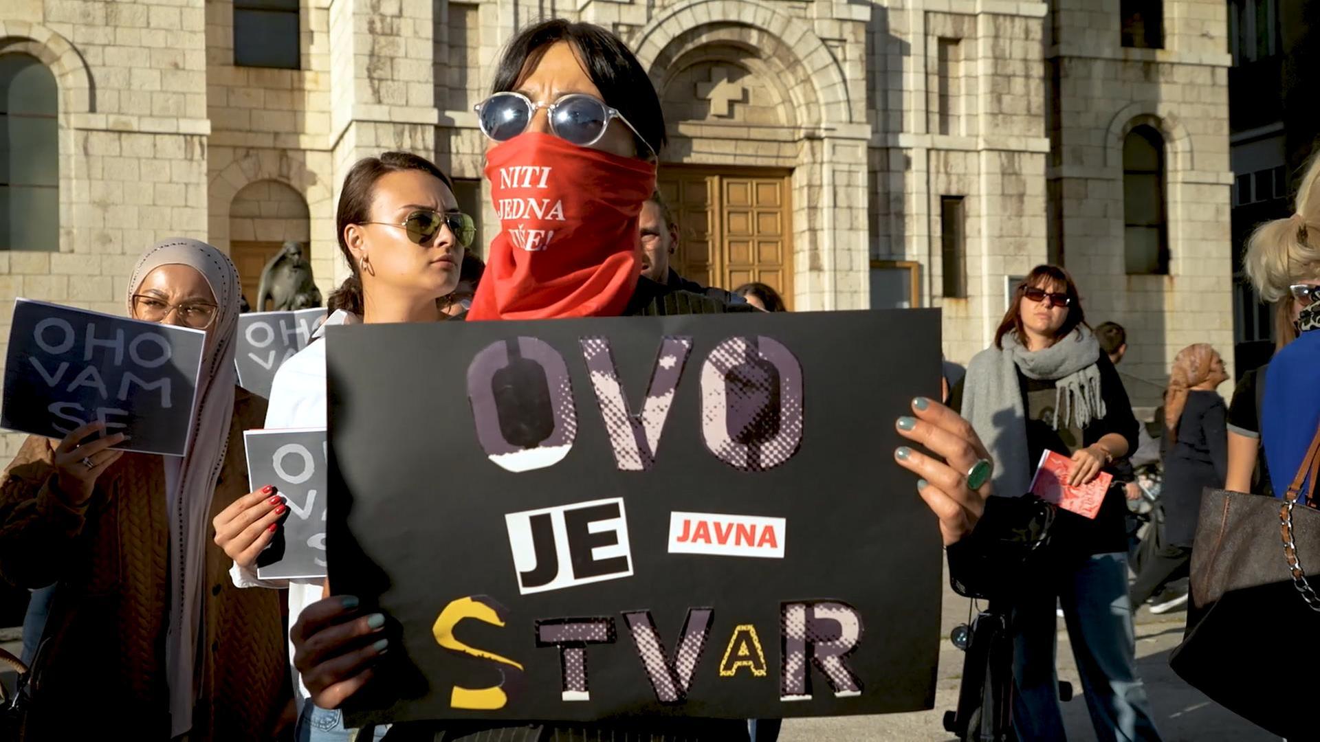 Eine Protestteilnehmerin hält ein Schild mit der Aufschrift: "Dies ist eine öffentliche Angelegenheit".
