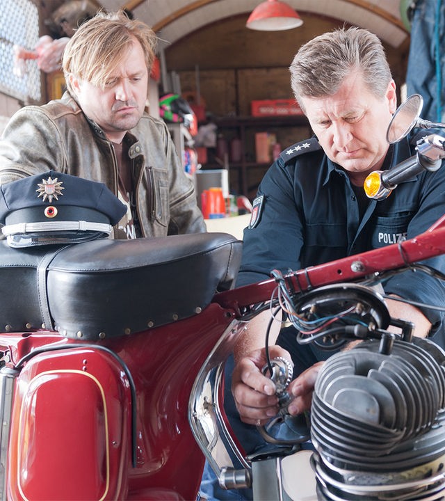 "Notruf Hafenkante - Gewinner und Verlierer": Jochen Kreuzer (Patrick von Blume) und Hans (Bruno F. Apitz) knien vor einem Motorrad, an dem Hans tüftelt.