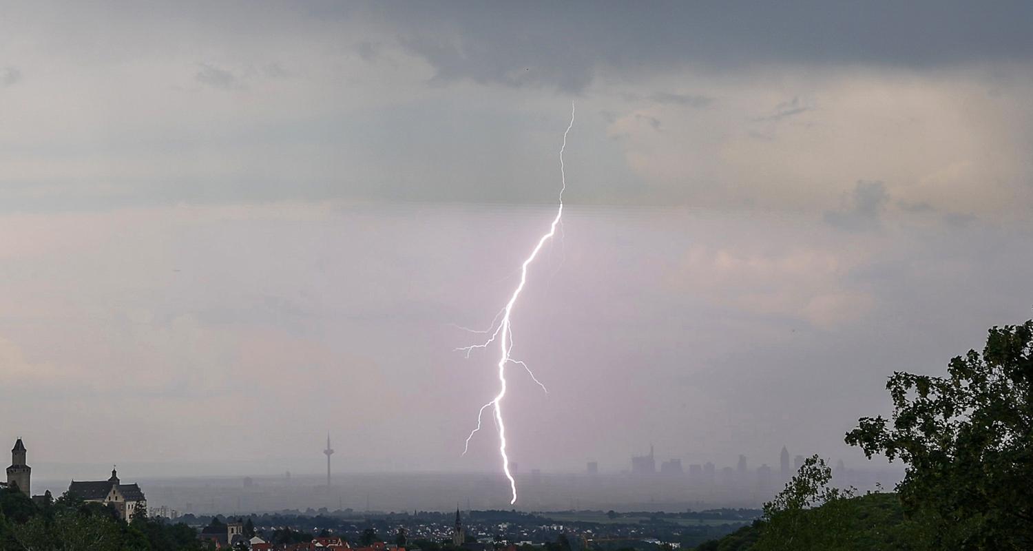 Hessen, Kronberg: Ein Blitz ist während eines Gewitters über der Skyline von Frankfurt am Main mit der Burg Kronberg (l) zu sehen.