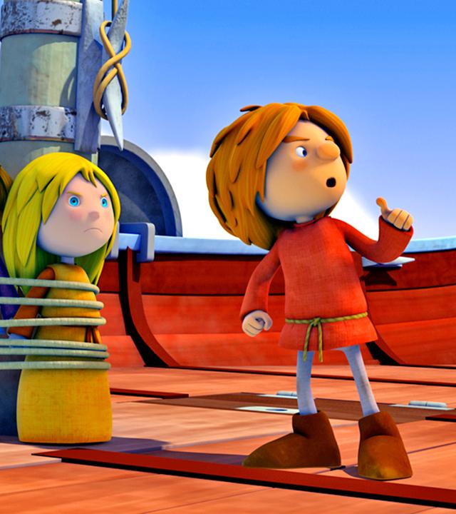 Wickie und Ilvy sind mit einem Seil am Mast festgebunden. Wickie wirkt überrascht, Ilvy sieht grimmig aus. Rechts neben ihnen steht Gilby. Alle schauen nach rechts. Im Hintergrund stehen weitere Wikingerkinder, die Gilby geschockt ansehen.