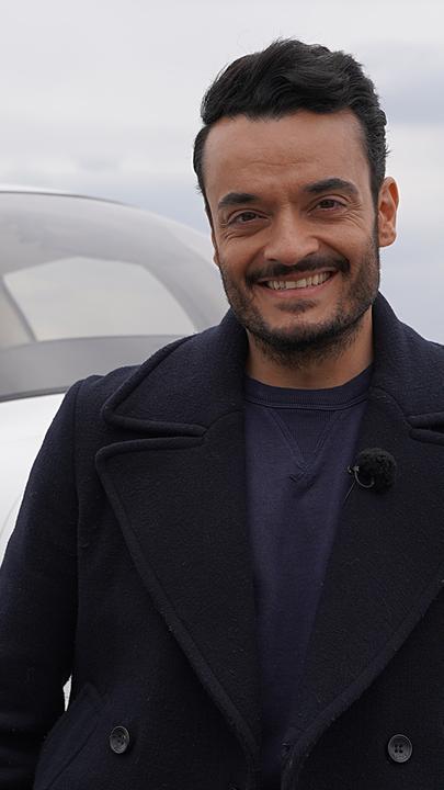 Giovanni ist an ein Kleinflugzeug gelehnt und lächelt in die Kamera.