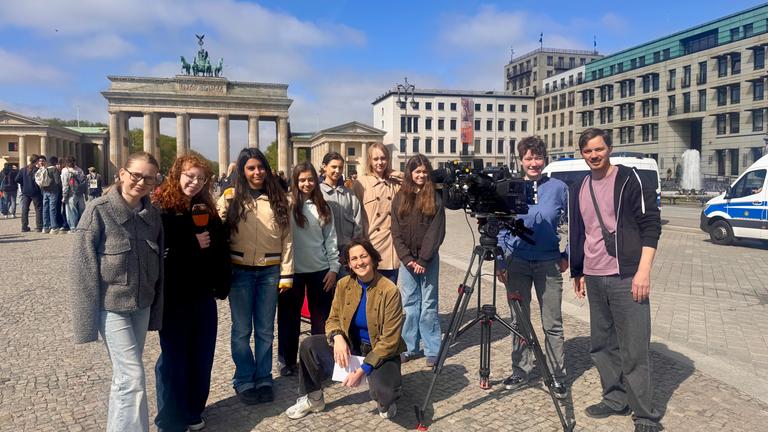Vor dem Brandenburger Tor posiert eine Gruppe von Mädchen und jungen Frauen zusammen mit einem Kamerateam für ein gemeinsames Foto. Neben ihnen steht eine professionelle Filmkamera auf einem Stativ, die ihren Einblick in die Praxis des ZDF beim Girls’ Day 2026 sichtbar macht.