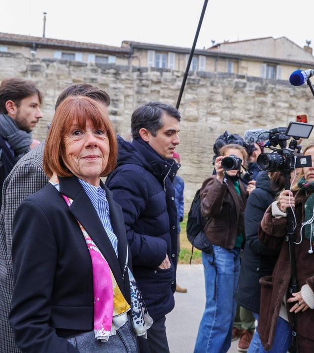 Eine Frau ist umringt von Reportern und Reporterinnen.