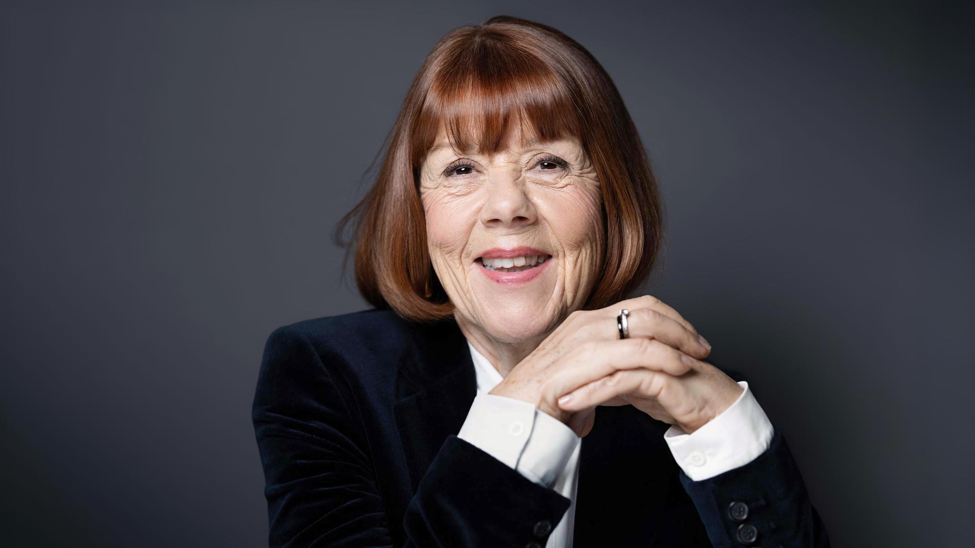 Eine ältere Frau mit Bop-Frisur blickt lächelnd in die Kamera