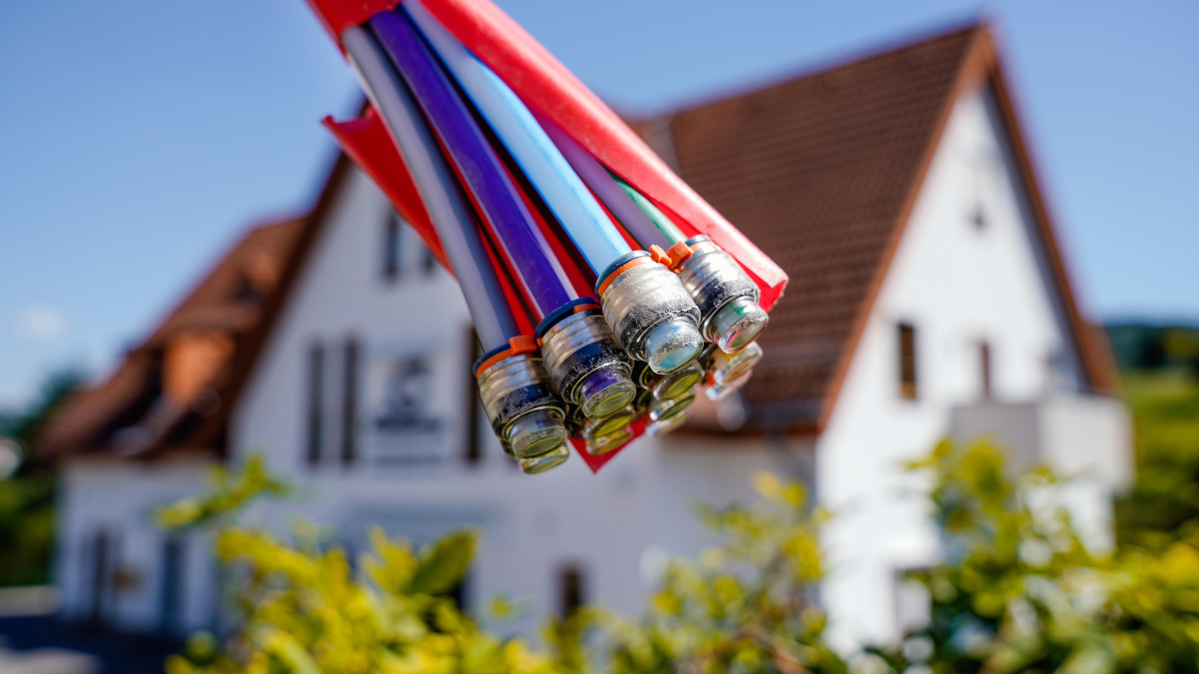 Ein Bündel mit Umhüllungen für Glasfaserkabel hängt vor einem Wohnhaus. Oberflockenbach, Baden-Württemberg.