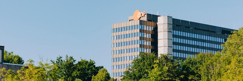Typical ZDF: Das ZDF Hochaus mit dem Logo auf dem Mainter Lerchenberg aus der Ferne mit Bäumen davor