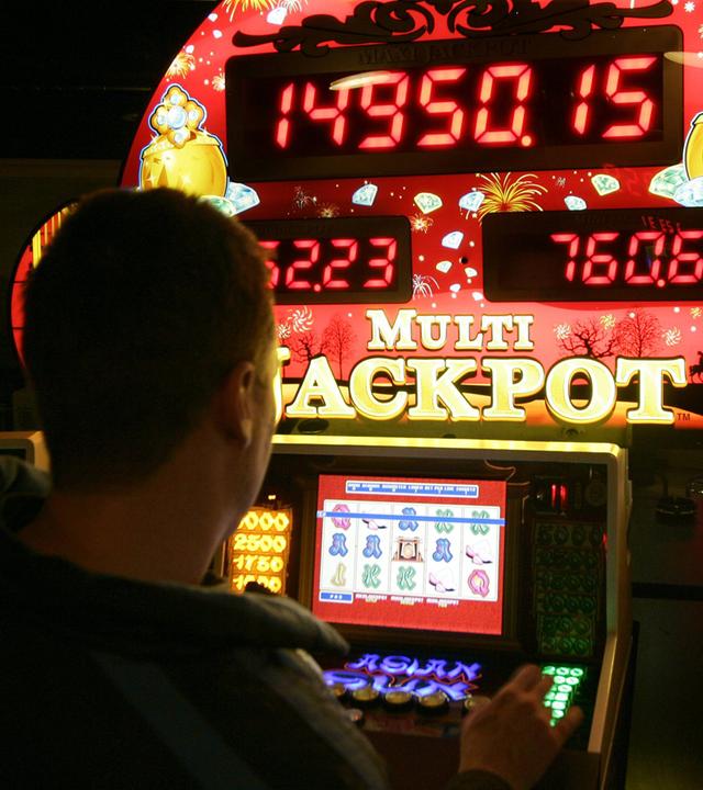 Mann spielt an einem Glücksspielautomaten in einer Spielhalle