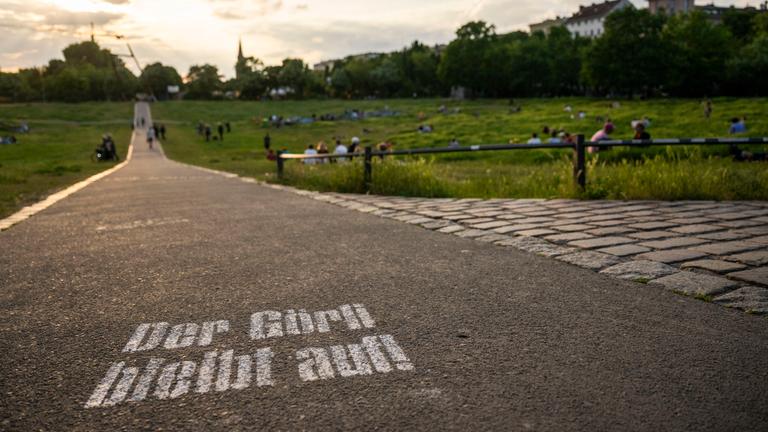 Besucher sitzen bei Sonnenuntergang im Görlitzer Park. 