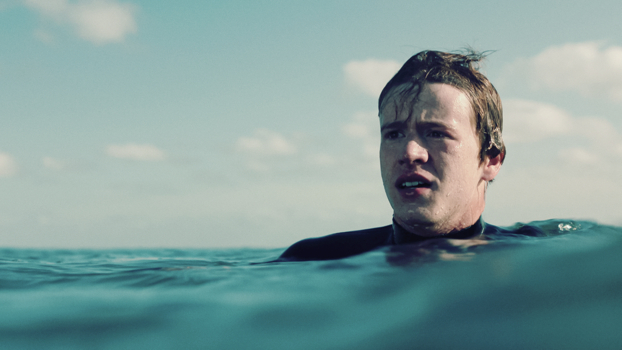 Ein Junge (Jonas Holdenrieder) in einem Neoprenanzug im Meer.