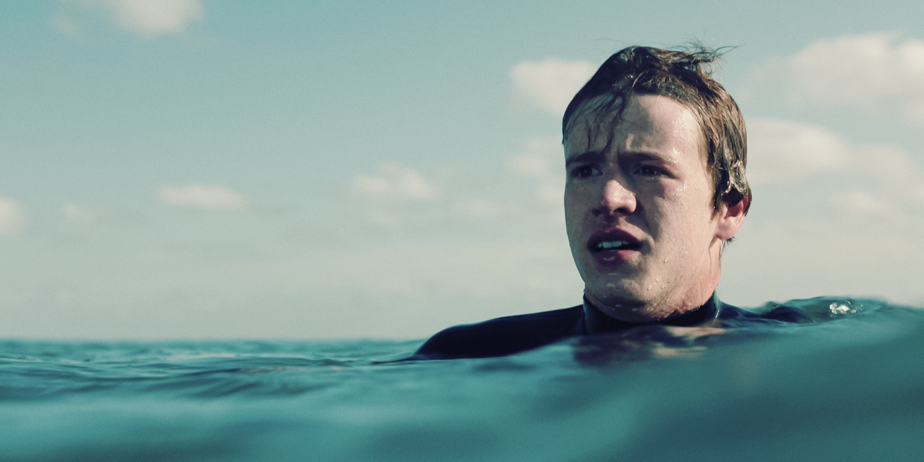 Ein Junge (Jonas Holdenrieder) in einem Neoprenanzug im Meer.