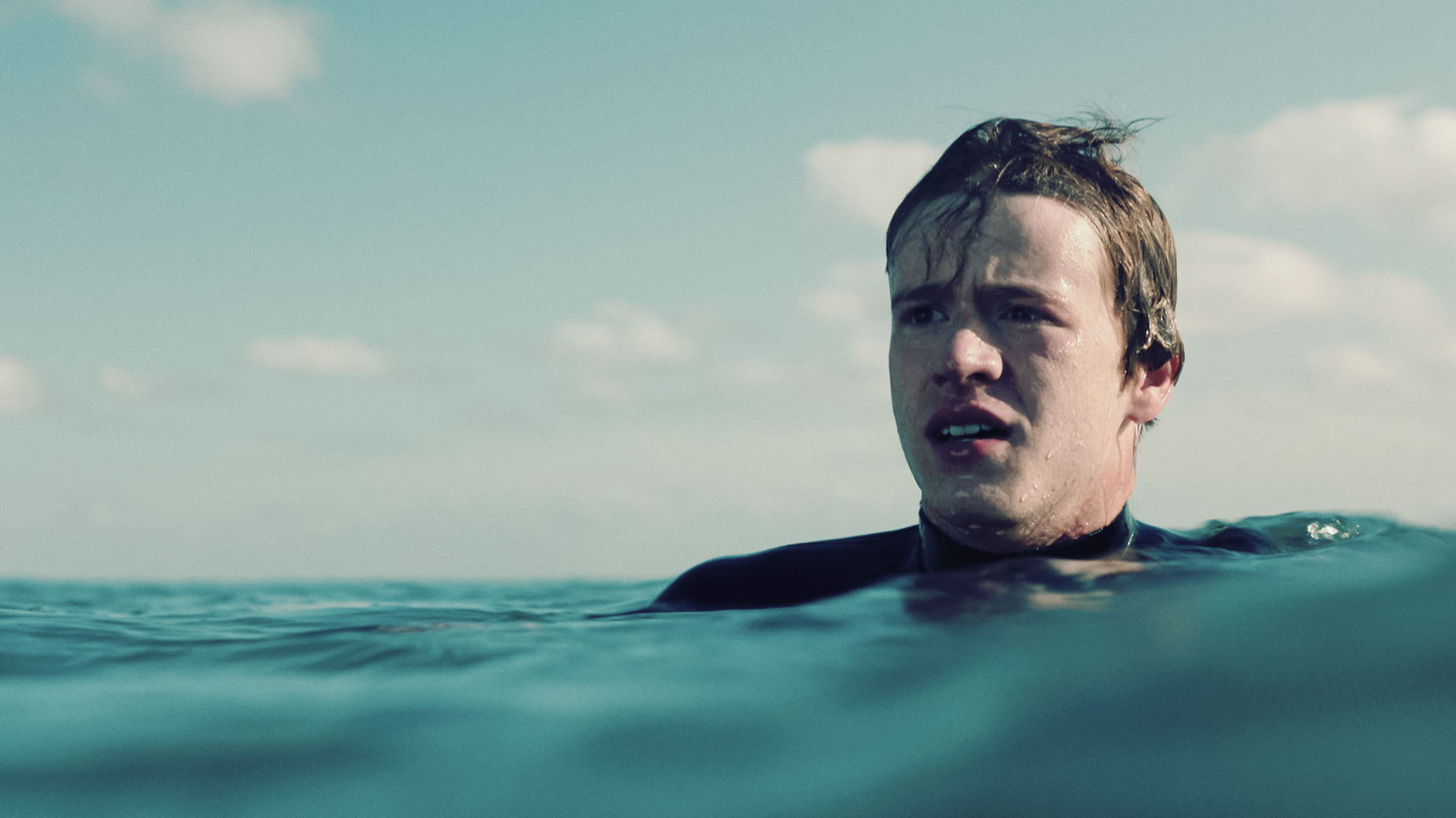 Ein Junge (Jonas Holdenrieder) in einem Neoprenanzug im Meer.