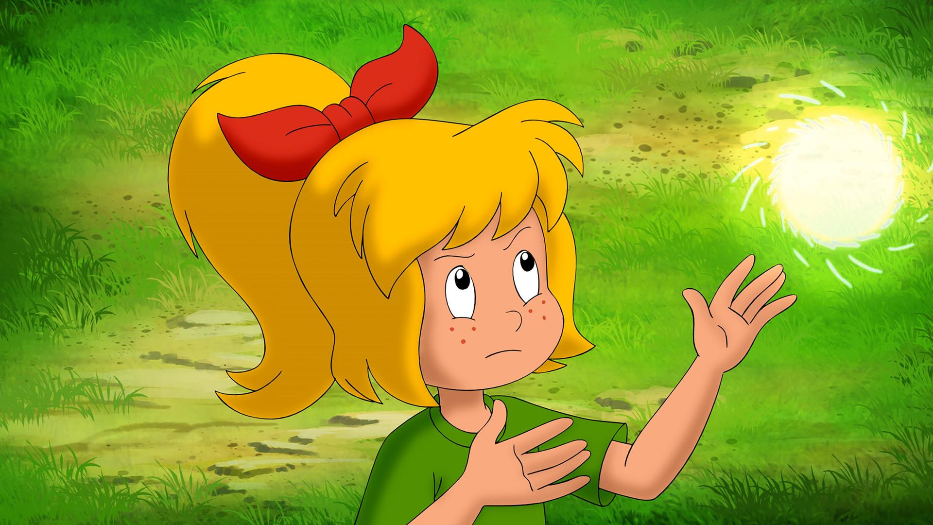 Bibi schaut angestrengt nach oben und ist gerade dabei, eine Lichthexerei zu üben. Über ihren Händen schwebt eine kleine, helle Kugel.