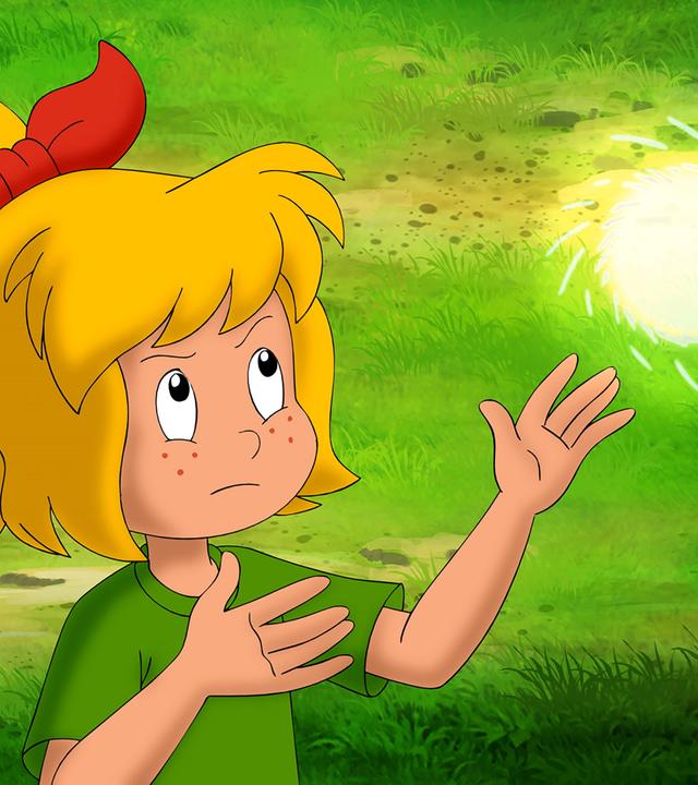 Bibi schaut angestrengt nach oben und ist gerade dabei, eine Lichthexerei zu üben. Über ihren Händen schwebt eine kleine, helle Kugel.