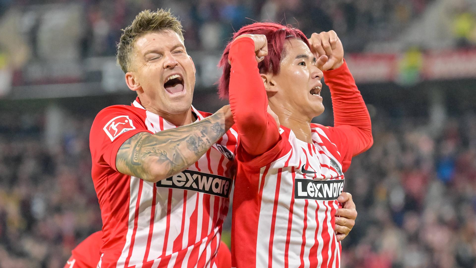 Der Freiburger Stürmer Keisuke Goto jubelt mit seinem Teamkollegen Lukas Kübler vor der Fankurver nach seinem Treffer zum 2:1 gegen den FC Schalke 04