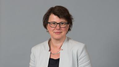 Porträt ZDF-Fernsehratsmitglied Cornelia Tausch vor grau-neutralem Hintergrund.