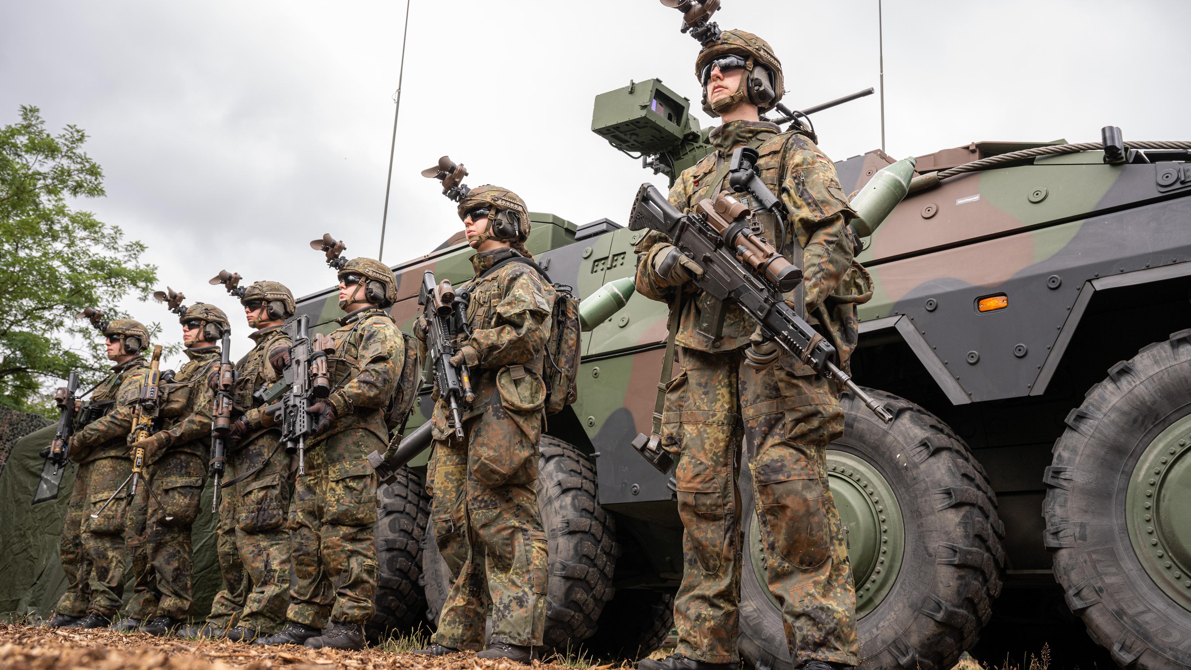 Niedersachsen, Munster: Bewaffnete Grenadiere im Ausrüstungszustand stehen auf dem Bundeswehrgelände vor einem GTK Boxer.