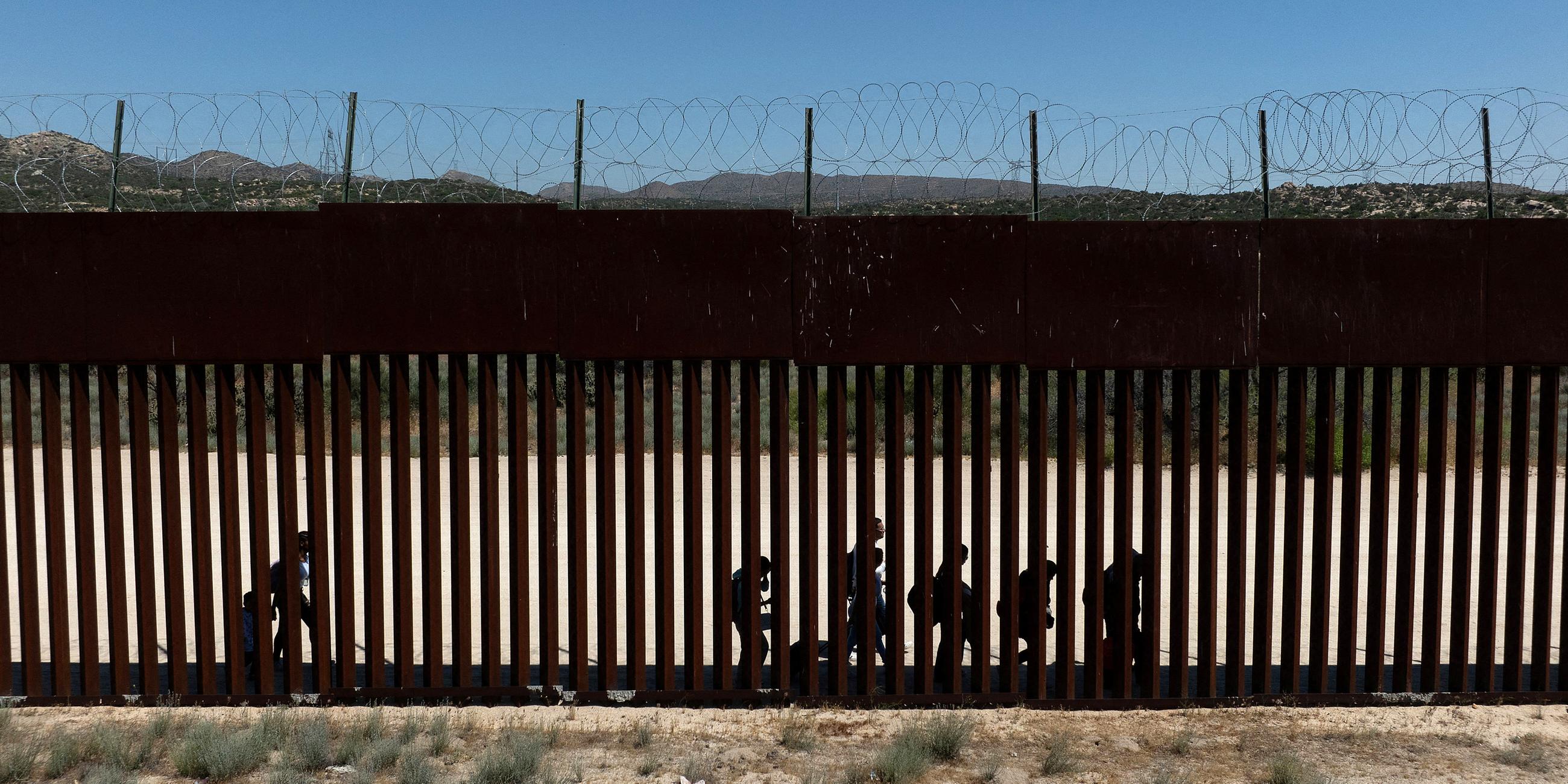 Migranten aus Kolumbien, Peru und Panama laufen nach dem Überqueren der Grenze in die USA entlang der Grenzmauer 