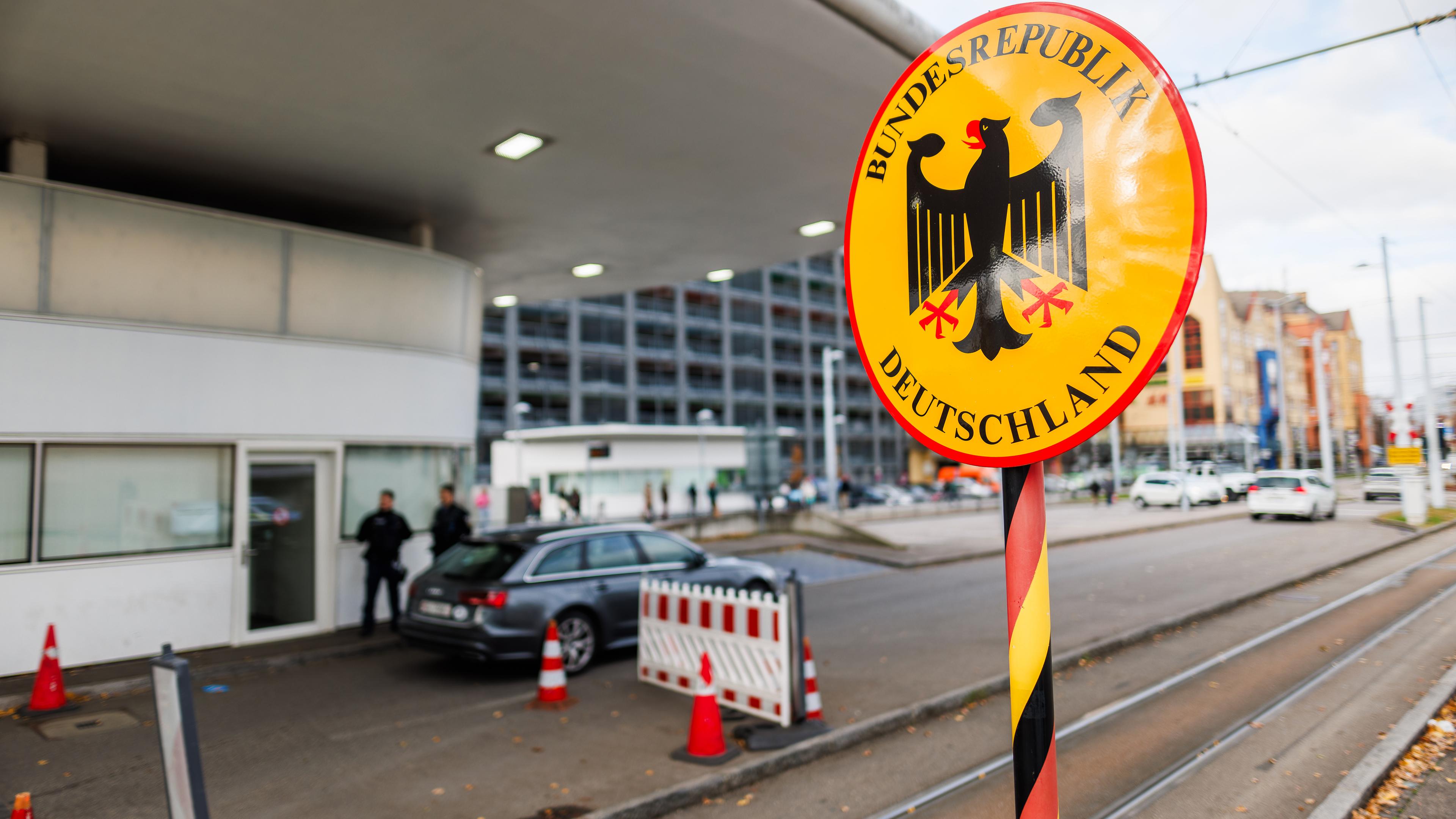 Ein Grenzschild steht am Grenzübergang in Weil am Rhein-Friedlingen während im Hintergrund zwei Beamte der Bundespolizei zu sehen sind.