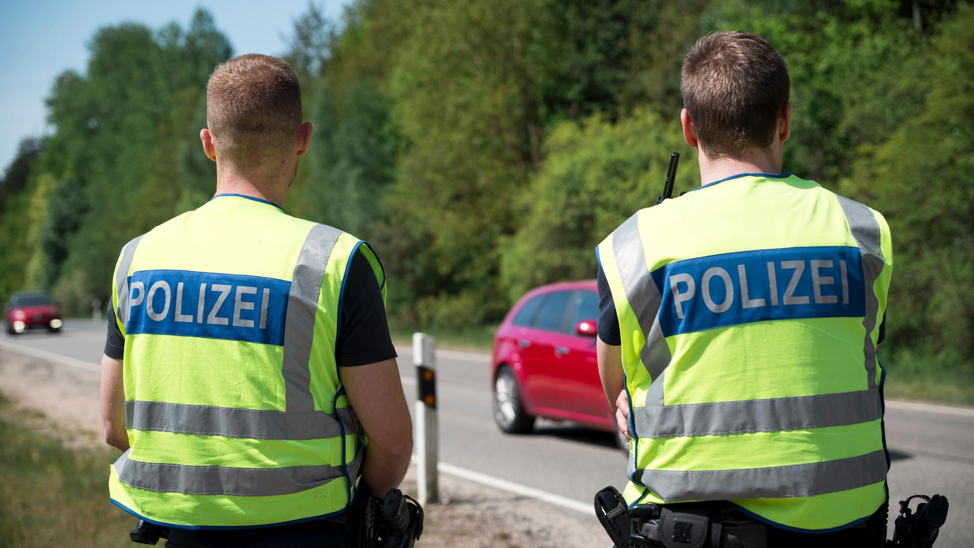 Einsatzkräfte der Polizei stehen an der Grenze zur Tschechischen Republik und überwachen den Verkehr. 