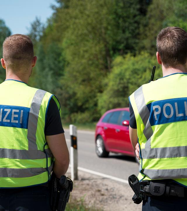 Einsatzkräfte der Polizei stehen an der Grenze zur Tschechischen Republik und überwachen den Verkehr. 