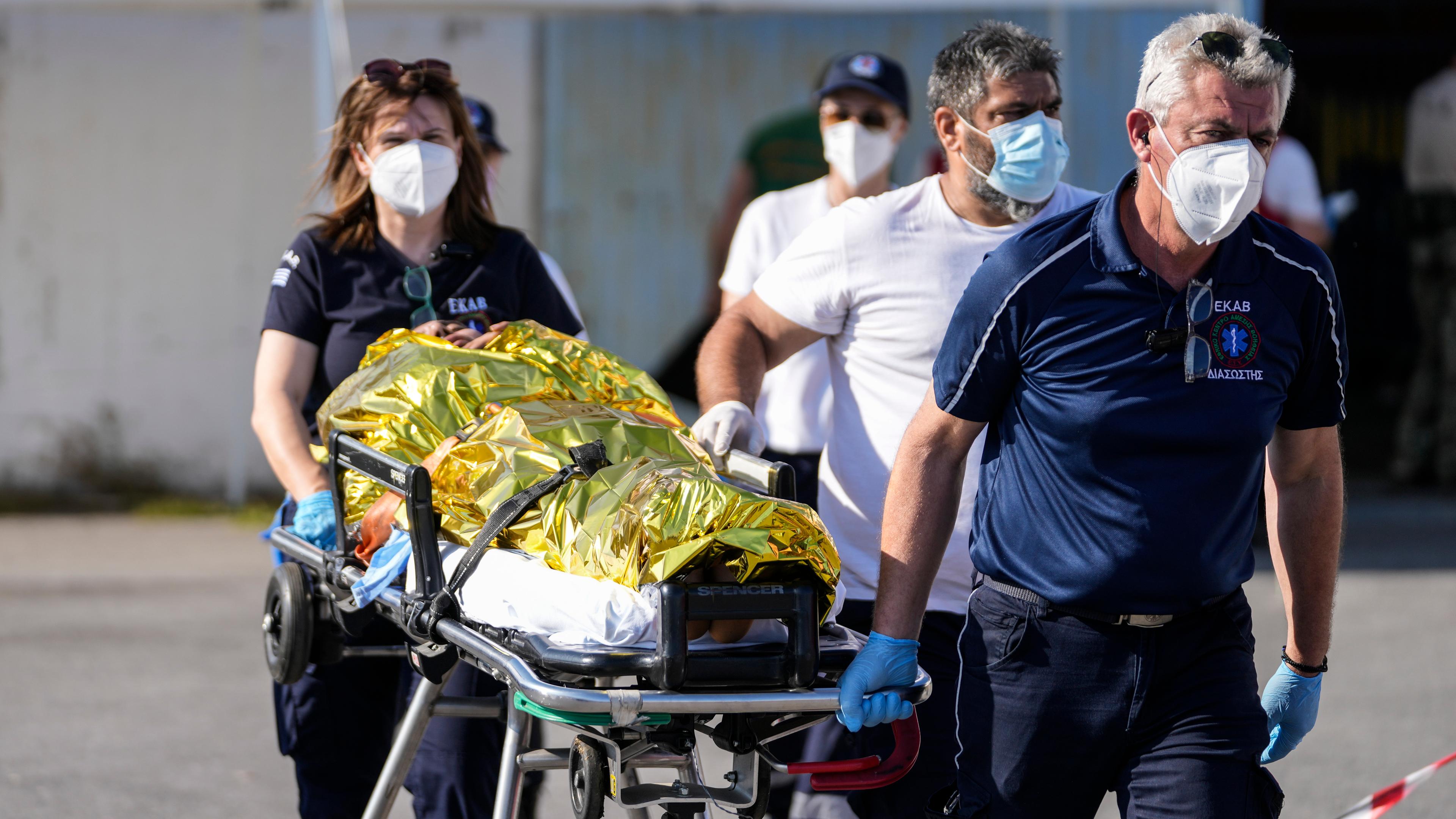 Rettungssanitäter transportieren einen Überlebenden des Bootsunglückes bei Griechenland auf einer Trage.