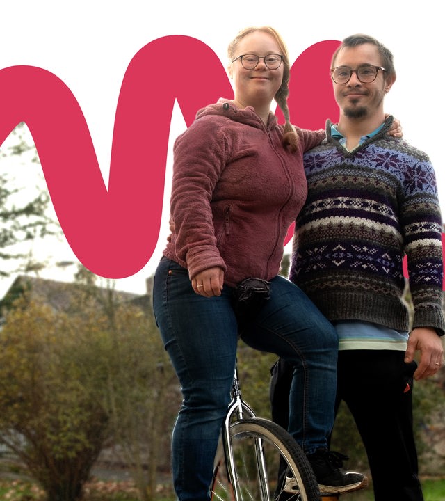 Hanna auf einem Einrad, lehnt sich an ihren Mann Silas 