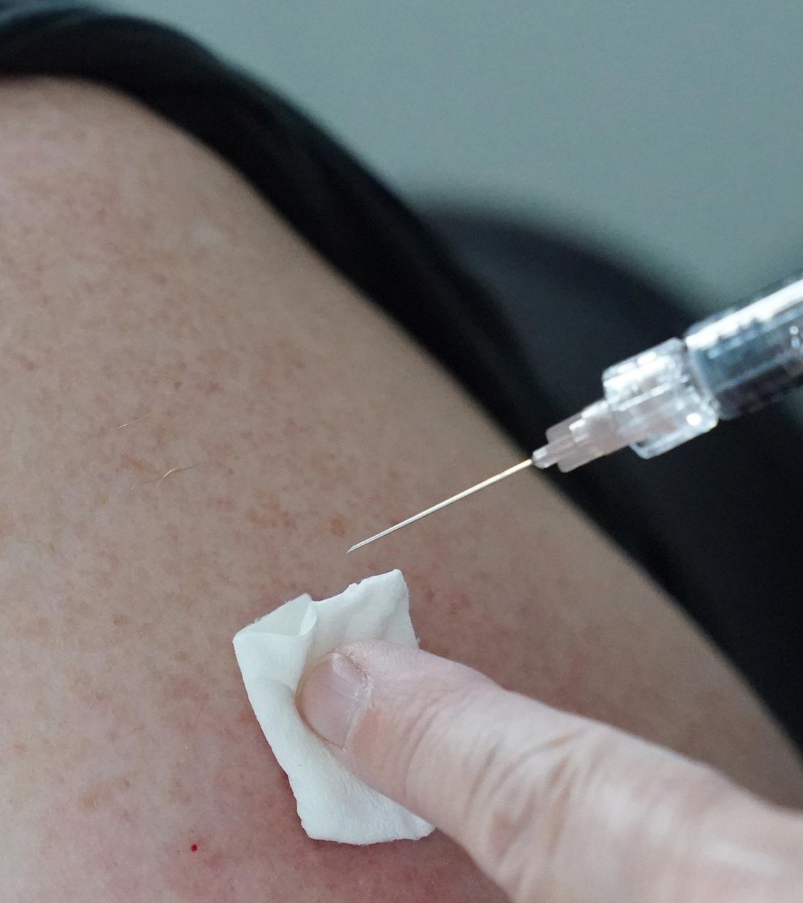 Eine Ärztin impft eine Person mit einem Impfstoff gegen Grippe