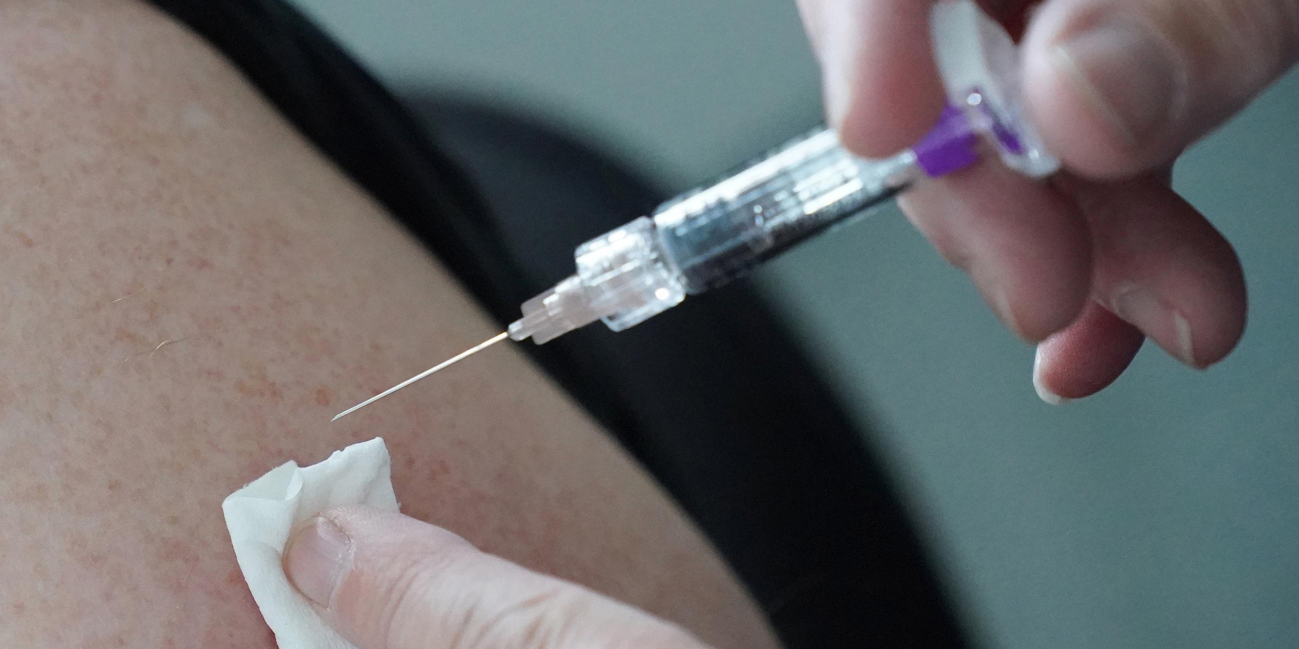 Eine Ärztin impft eine Person mit einem Impfstoff gegen Grippe