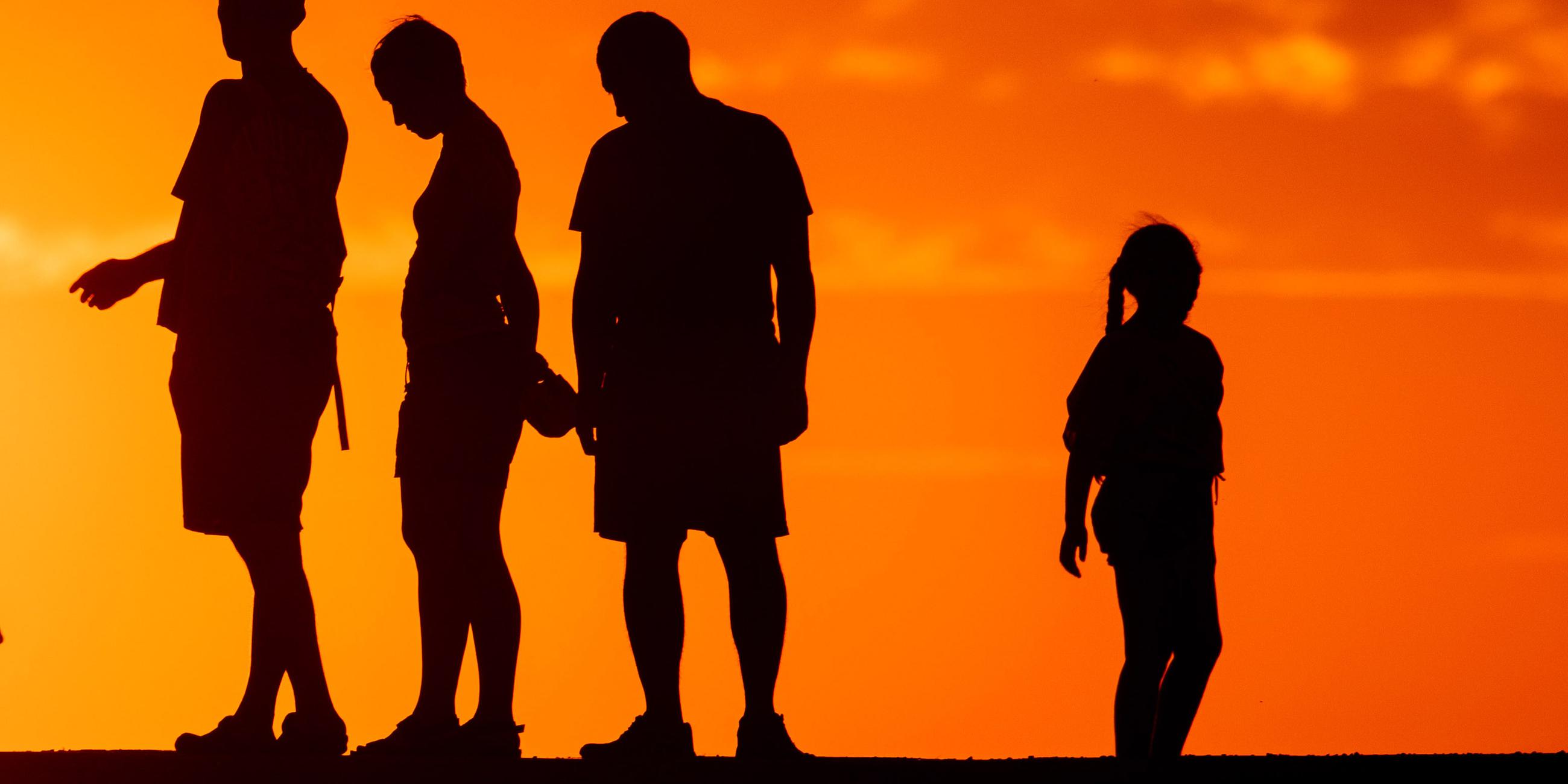 Symbolbild: Menschen stehen vor der untergehenden Sonne zusammen.