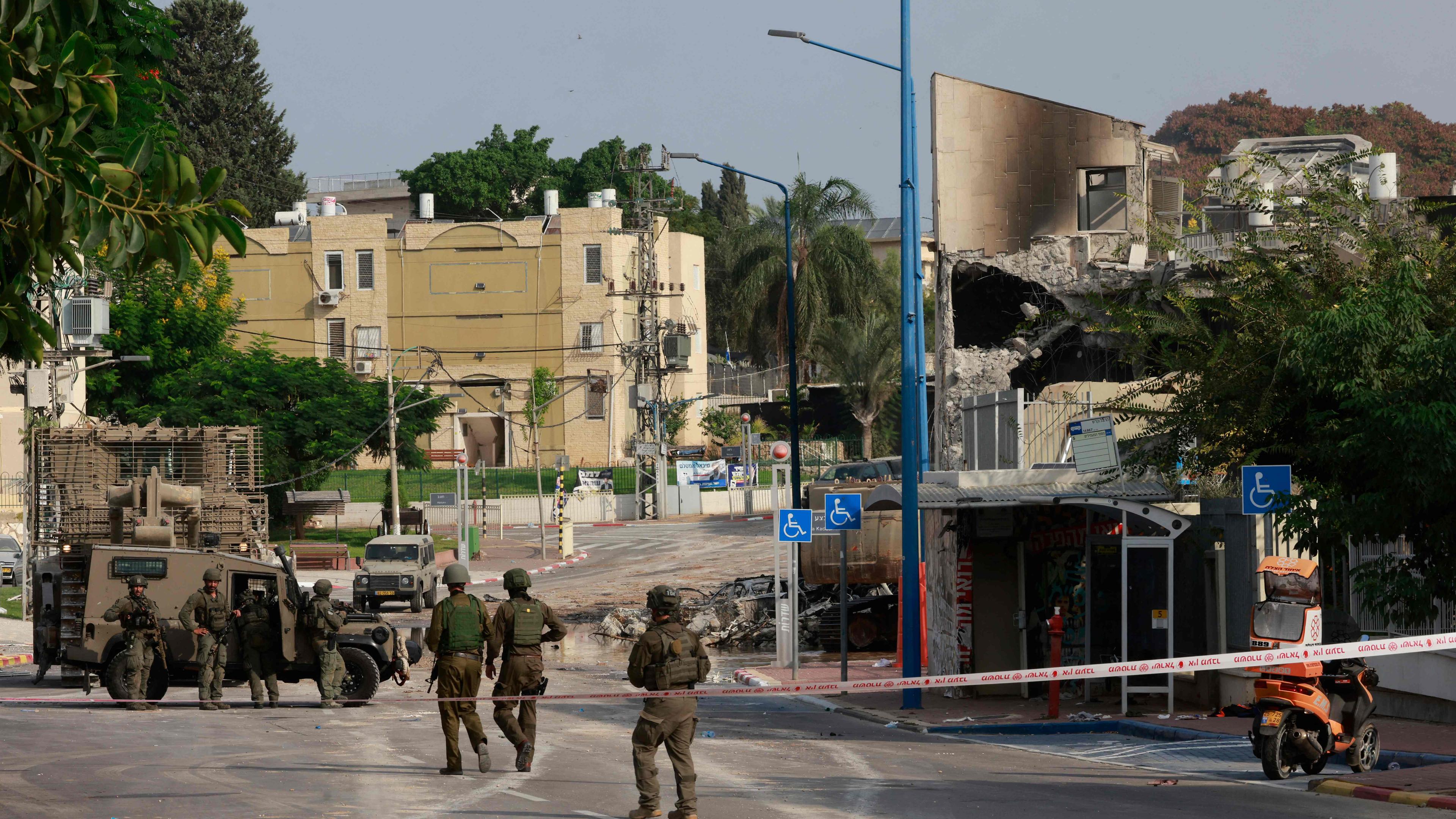 Israeli troops gather around a cordoned-off Israeli police station that was damaged during battles the previous day to dislodge Hamas militants who were stationed inside, on October 8, 2023.