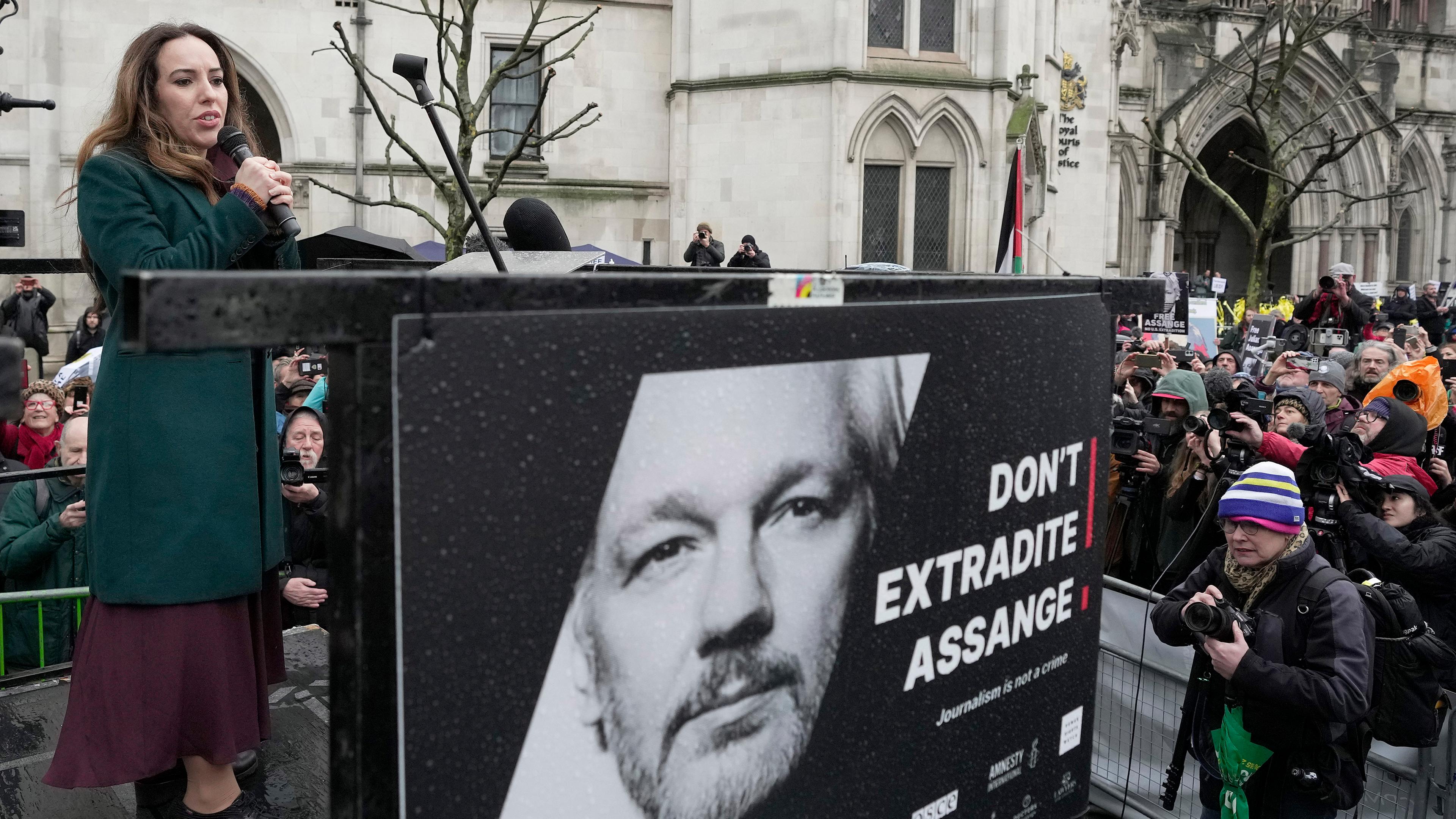Stella Assange, Ehefrau von Julian Assange, spricht neben einem Plakat von Julian Assange vor dem Royal Courts of Justice in London
