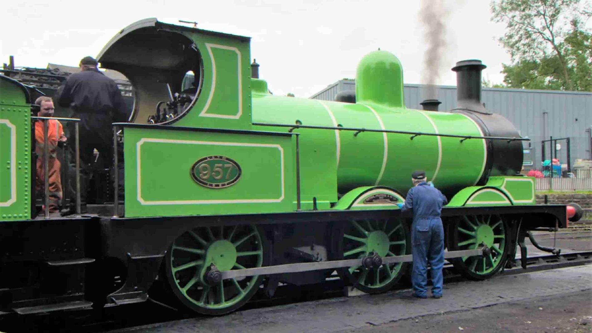 Drei Männer in Oberalls arbeiten an der Lokomotive 957 alias „Der Grüne Drache“.