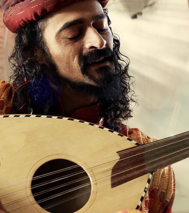 Ein Mann in historischer Kleidung singt und spielt eine Laute.