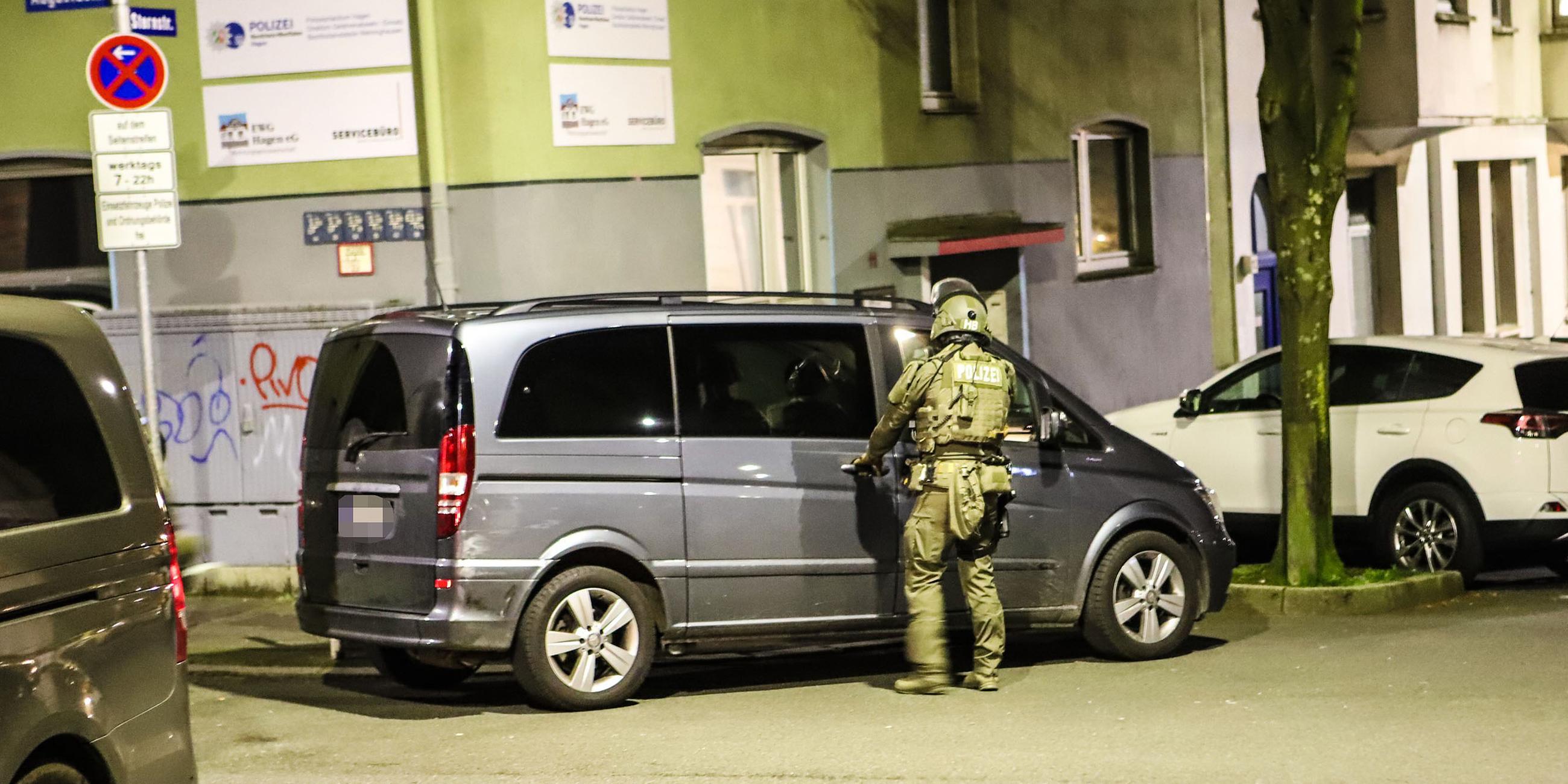 Ein Polizist steht während einer Razzia an einem Van, aufgenommen am 03.05.2023 in Hagen