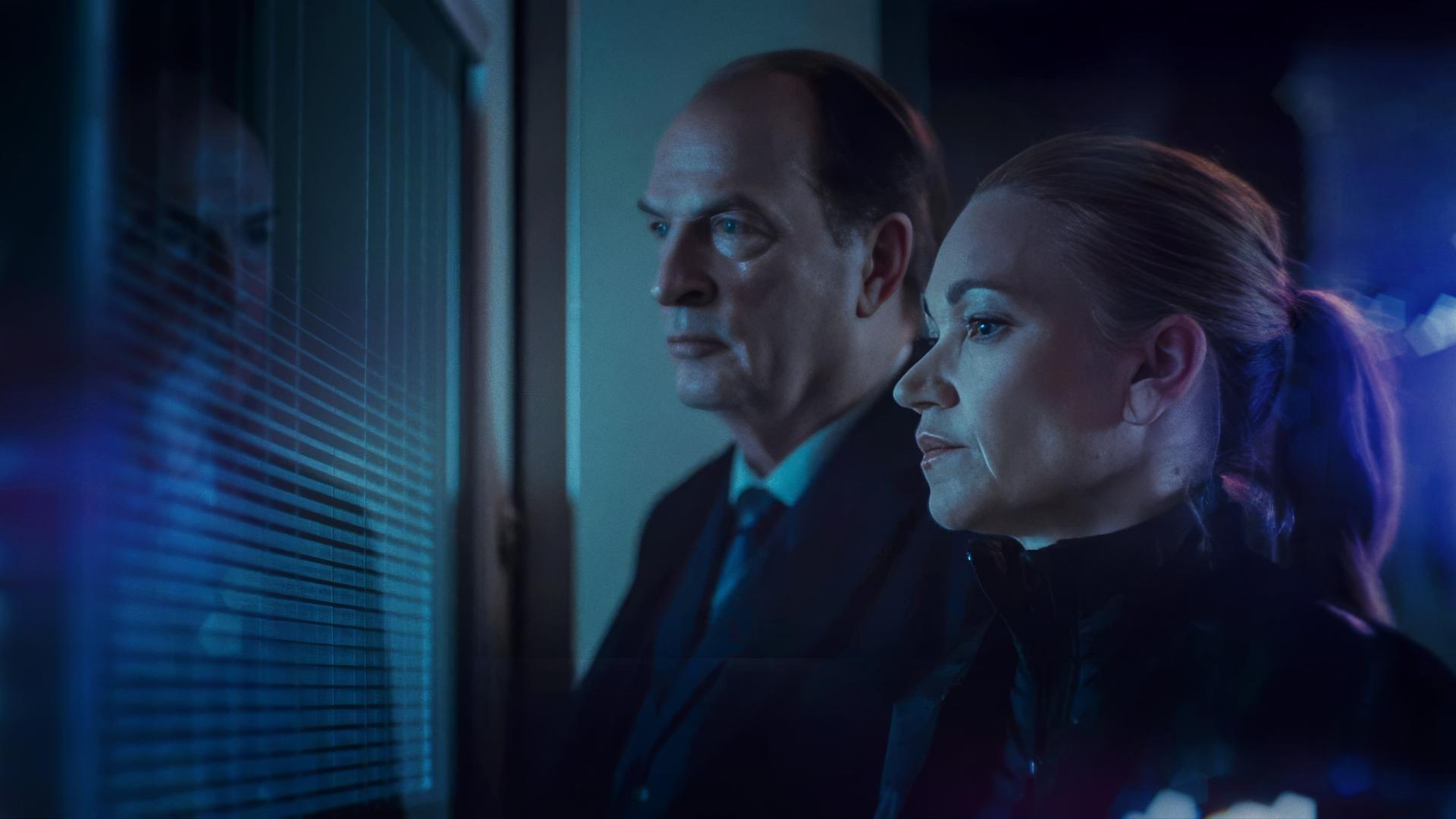 Sarah Kohr (Lisa Maria Potthoff), eine blonde Frau mit streng zurückgebundenen Haar, und Anton Mehringer (Herbert Knaup), ein etwas älterer Mann im Anzug, stehen an einem Fenster und blicken ernst nach draußen.