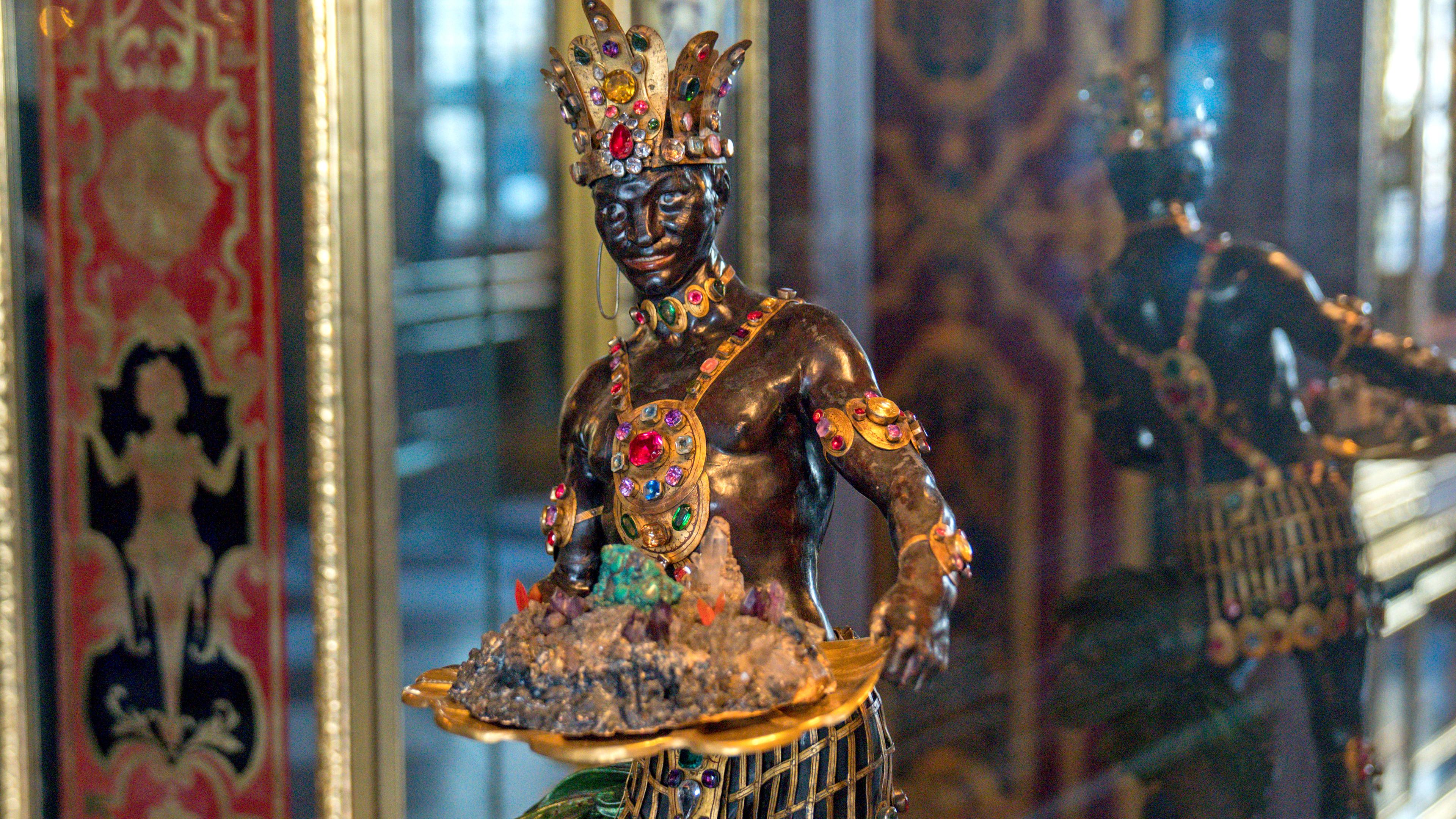 Die Skulptur eines Mohren trägt ein Tablett mit Gesteinsbröckchen und Kristallen. 