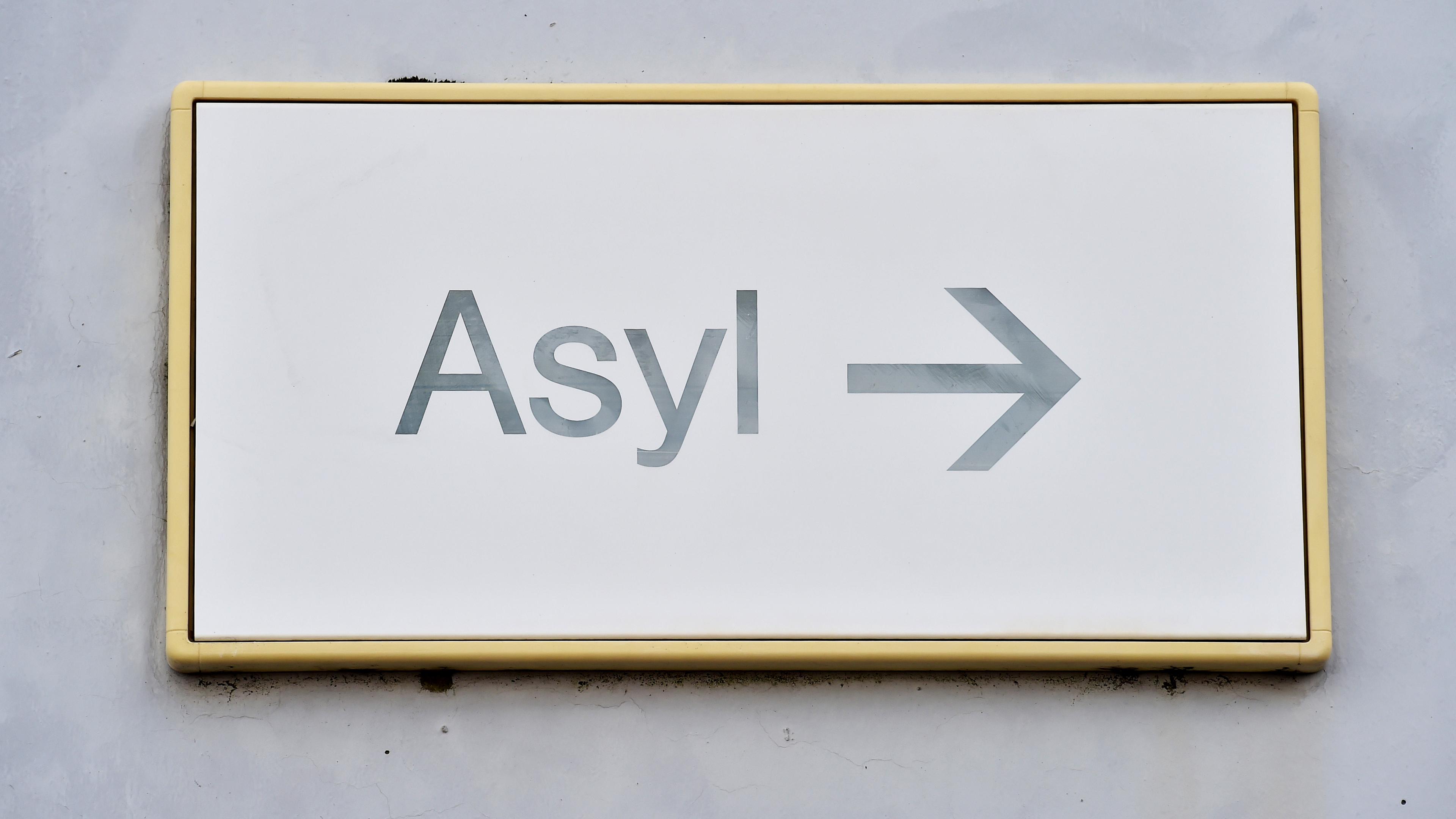 ARCHIV - 04.08.2014, Baden-Württemberg, Karlsruhe: Ein Schild mit der Aufschrift «Asyl» hängt in der Landeserstaufnahme für Asylbewerber (LEA) an einer Wand.