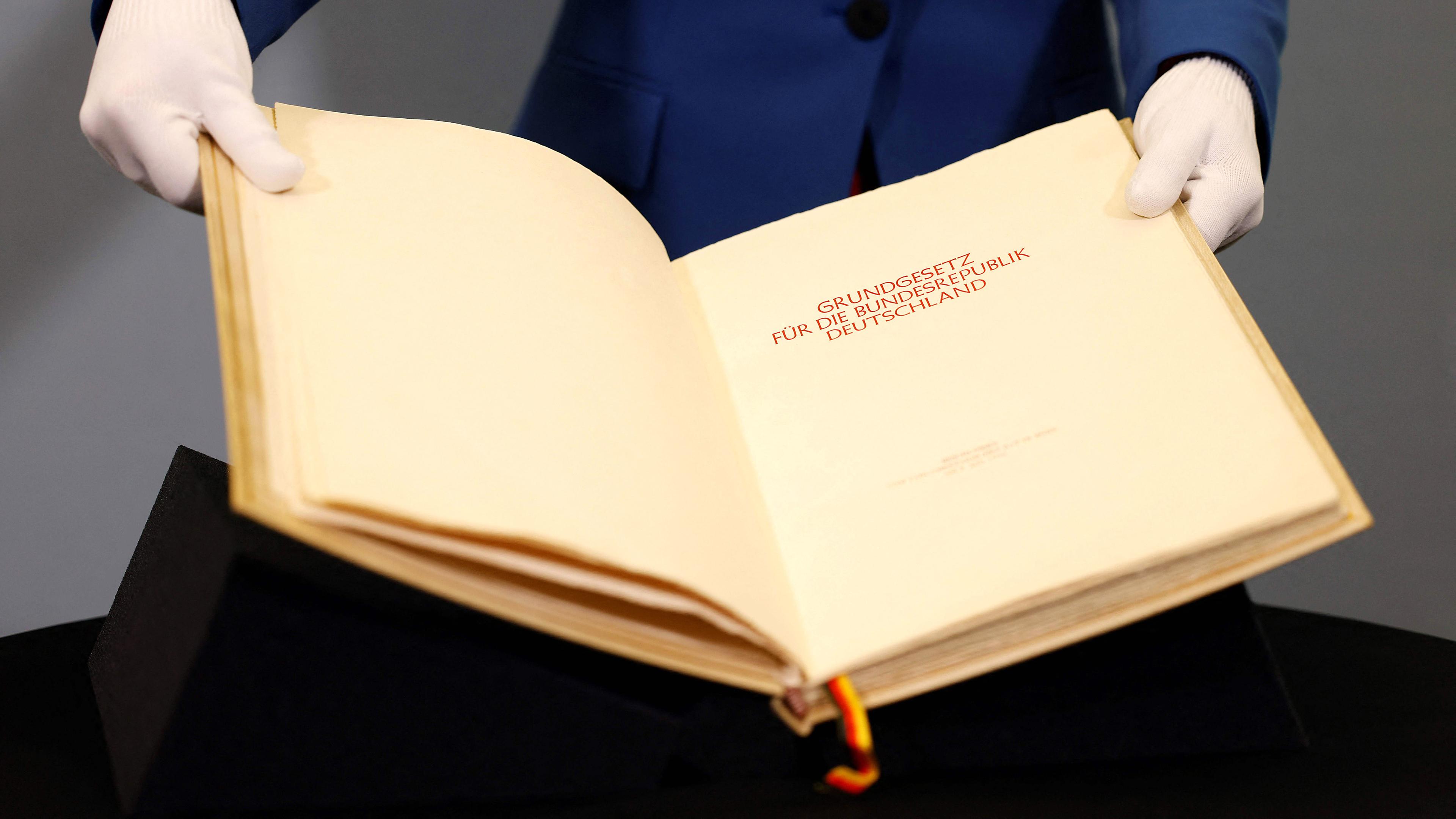 Ein Berater des Parlamentarischen Archivs des Bundestages zeigt die Seiten des Originalbuchs des Grundgesetzes, aufgenommen am 11.03.2024