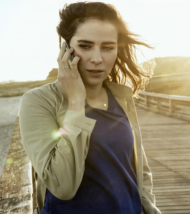 Emma (Nora Tschirner) steht telefonierend am Strand.