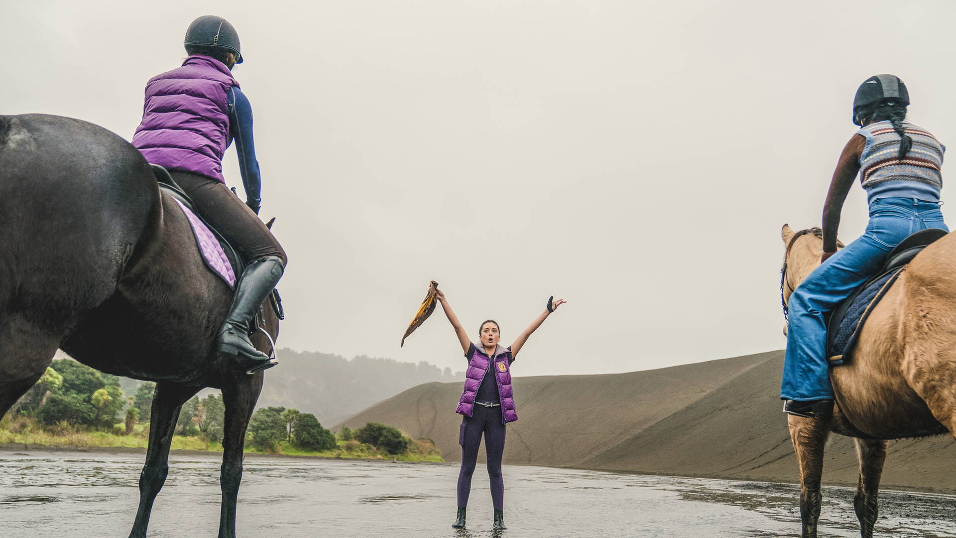 Nicole und Caroline sitzen auf ihren Pferden und warten auf das Startsignal von Bianca, die ihre Arme ausgestreckt nach oben hält. In ihrer rechten Hand hält sie ein Tuch.