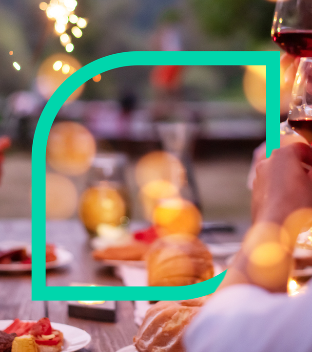 Menschen prosten sich an einem Tisch mit Weingläsern zu